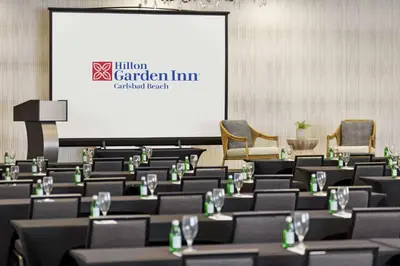 a conference room with tables and chairs and a screen at Hilton Garden Inn Carlsbad Beach in Carlsbad