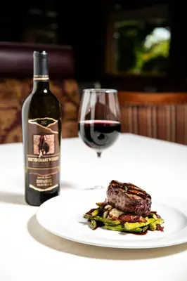 a plate of steak and a bottle of wine and a glass at South Coast Winery Resort & Spa in Temecula