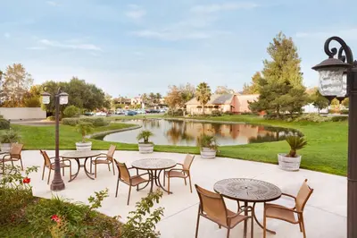 a patio with tables and chairs and a pond at Embassy Suites by Hilton Temecula Valley Wine Country in Temecula