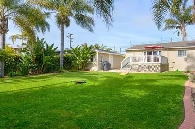 a yard with palm trees and a house at Ultimate Beach Bungalow - 1 block from beach - huge backyard in Carlsbad