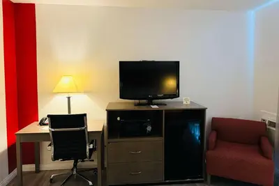 a room with a desk with a television and two chairs at Ramada by Wyndham San Diego Airport in San Diego