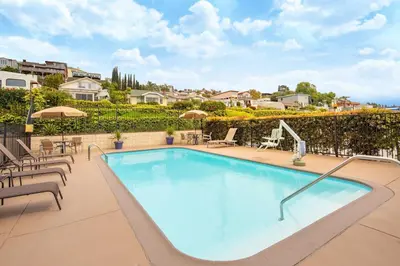 a swimming pool with chairs and umbrellas on a patio at Holiday Inn Express San Diego Airport-Old Town by IHG in San Diego