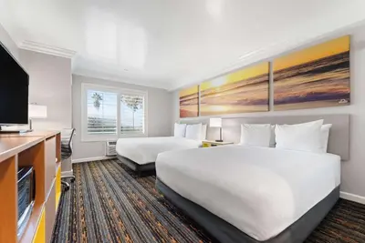 a hotel room with two beds and a flat screen tv at Days Inn by Wyndham San Diego Hotel Circle in San Diego