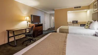 a hotel room with two beds and a desk with a computer at Best Western Plus Dana Point Inn-by-the-Sea in Dana Point