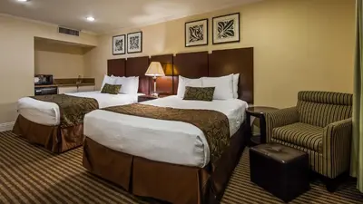 a hotel room with two beds and a chair at Best Western Plus Dana Point Inn-by-the-Sea in Dana Point