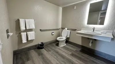 a bathroom with a toilet and a sink and a mirror at Days Inn by Wyndham San Diego Vista in Vista