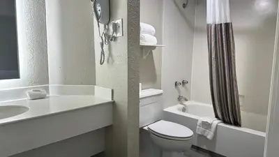 a white bathroom with a toilet and a sink at Days Inn by Wyndham San Diego Vista in Vista