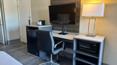 a room with a desk with a television and a chair at Days Inn by Wyndham San Diego Vista in Vista