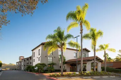 a building with palm trees in front of a street at La Quinta Inn by Wyndham San Diego - Miramar in Sabre Springs