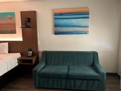 a bedroom with a green couch next to a bed at La Quinta Inn by Wyndham San Diego - Miramar in Sabre Springs