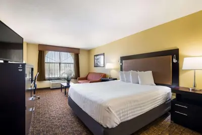 a hotel room with a large bed and a chair at Best Western Escondido Hotel in Escondido