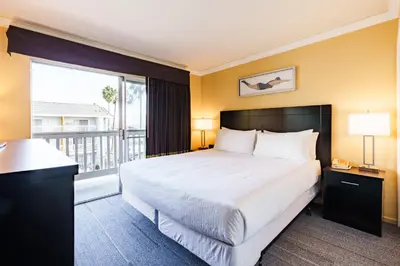 a bedroom with a large bed and a balcony at Dana Point Marina Inn in Dana Point