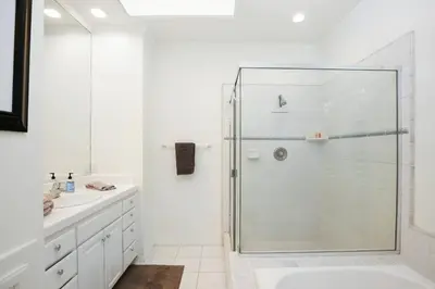a white bathroom with a glass shower stall at 416 Dahlia in Newport Beach
