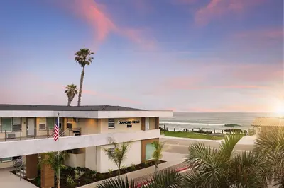 a building with a palm tree in front of the ocean at Diamond Head Inn in San Diego