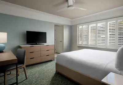 a bedroom with a bed and a desk and a television at Diamond Head Inn in San Diego