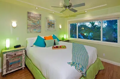 a bedroom with a bed with a ceiling fan and a window at Ocean Palms Beach Resort in Carlsbad