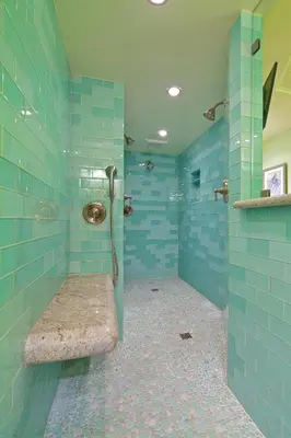 a blue tiled bathroom with a shower with a bench at Ocean Palms Beach Resort in Carlsbad