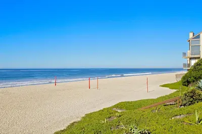 a beach with red poles in the sand and the ocean at Ocean Palms Beach Resort in Carlsbad