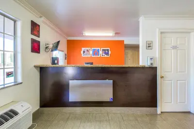 a living room with an orange wall and a counter at Motel 6-Menifee, CA in Menifee