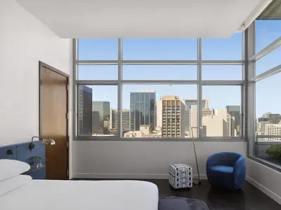 a bedroom with a large window with a city view at Alma San Diego Downtown, a Tribute Portfolio Hotel in San Diego