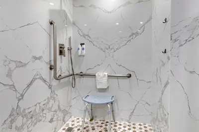 a shower with a blue stool in a bathroom with marble walls at Comfort Inn & Suites Irvine Spectrum in Lake Forest