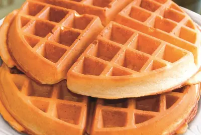 a stack of waffles on a white plate at La Quinta Inn & Suites by Wyndham Irvine Spectrum in Irvine
