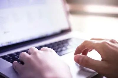 a person is typing on a laptop computer at La Quinta Inn & Suites by Wyndham Irvine Spectrum in Irvine