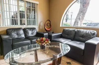 a living room with a leather couch and a glass table at Rodeway Inn Escondido Downtown in Escondido