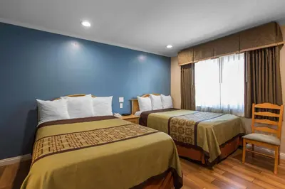 a hotel room with two beds and a chair at Rodeway Inn Escondido Downtown in Escondido