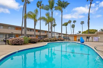 a swimming pool in front of a hotel with palm trees at Hotel Palmeras Chula Vista in Chula Vista