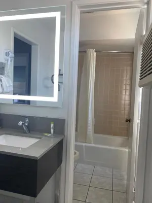 a bathroom with a sink and a tub and a mirror at Hotel Palmeras Chula Vista in Chula Vista