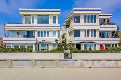 a large white house on the beach next to the sand at 125-Fun In The Sun Penthouse in San Diego
