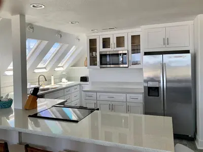 a kitchen with white cabinets and a stainless steel refrigerator at 125-Fun In The Sun Penthouse in San Diego