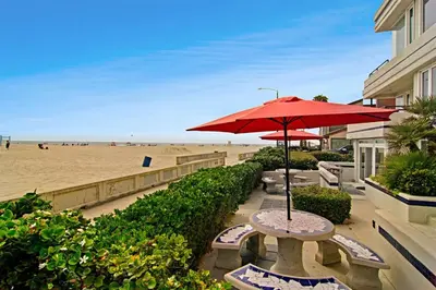 a table with a red umbrella next to the beach at 125-Fun In The Sun Penthouse in San Diego
