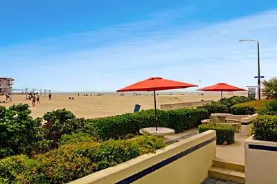 a beach with tables and umbrellas and people on the beach at 125-Fun In The Sun Penthouse in San Diego