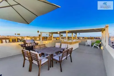 a patio with a table and chairs on a roof at 200-Surf Stars Penthouse in San Diego