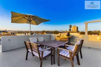 a table and chairs on a balcony with an umbrella at 200-Surf Stars Penthouse in San Diego