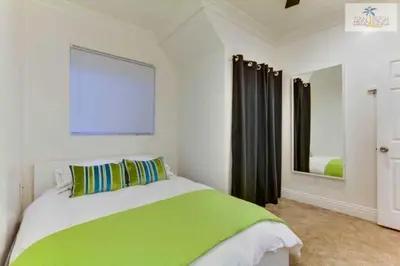 a bedroom with a green and white bed and a mirror at 201-Surf Stars Studio in San Diego
