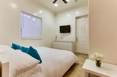 a bedroom with a white bed with blue pillows and a tv at 199-Surf Stars Combo in San Diego
