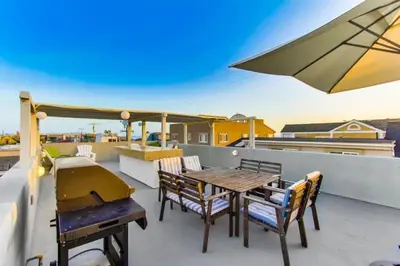 a patio with a table and chairs on a roof at 199-Surf Stars Combo in San Diego