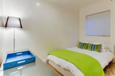 a white bedroom with a green bed and a table at 199-Surf Stars Combo in San Diego