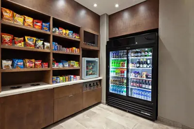 a kitchen with a refrigerator and shelves of food at SpringHill Suites by Marriott Escondido Downtown in Escondido