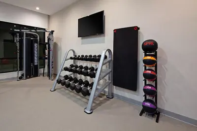 a gym with a rack of dumbbells and a tv at SpringHill Suites by Marriott Escondido Downtown in Escondido