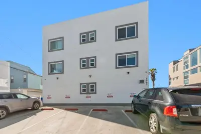 a white building with two cars parked in a parking lot at 101-Luxury1 in San Diego