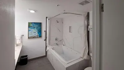 a white bathroom with a tub and a shower at Clarion Pointe El Cajon San Diego East in El Cajon