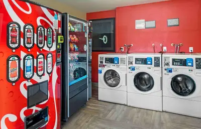 a laundry room with three washing machines and a soda machine at Extended Stay America Suites - Orange County - Irvine Spectrum in Irvine