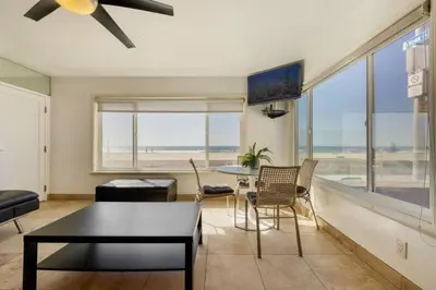a living room with a table and chairs and a large window at 107-Oceanfront Lux 17 in San Diego