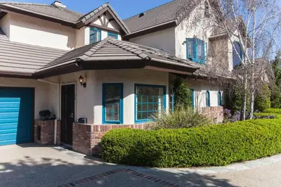 a white house with a blue door and bushes at Castlegate Guest Apartment in Vista
