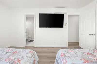a white bedroom with two beds and a flat screen tv at 103-Luxury3 in San Diego