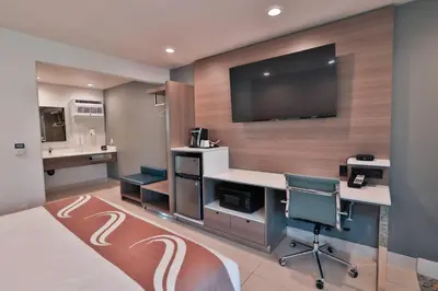 a hotel room with a desk and a flat screen tv at Rodeway Inn San Clemente in San Clemente